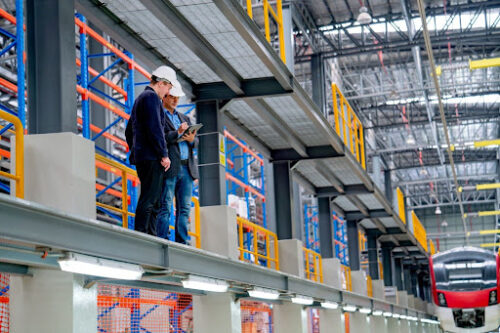 Warehouse workers standing on double height vertical pallet racking system in large distribution center